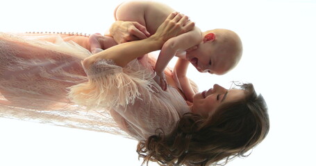Vertical shot of a beautiful mother holding a small naked child in her arms. A young mother with a beautiful hairstyle and makeup holds a baby in her arms. Close up, slow motion
