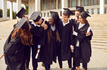 Portrait of a group of smiling happy multiracial international graduates students hugging and...