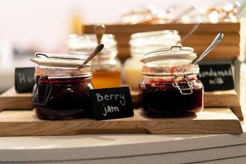 close-up breakfast buffet line serving a variety of jams in a hotel with hospitality signs