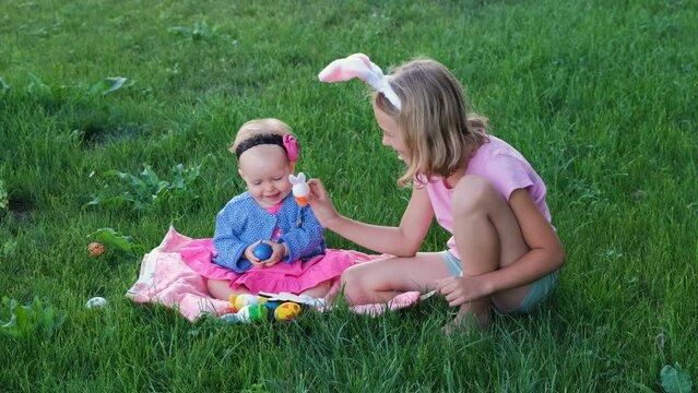 Cute kids playing with colorful eggs and decorations on the grass, slow motion. Easter hunt concept