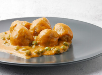 Close up, homemade plate of meatballs with tomato sauce and peas.