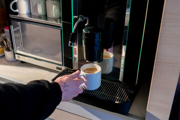 close-up of the process of making fragrant coffee with an automatic coffee machine, a person takes the drink