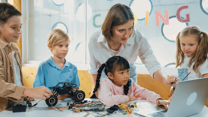 Smart teacher and diverse student looking at laptop on table with car model placed. Caucasian...