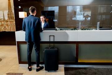 The receptionist at the counter meets the guest with luggage in the hotel business travel...