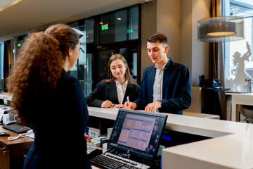 The receptionist at the counter meets guests with luggage in the hotel business travel hospitality