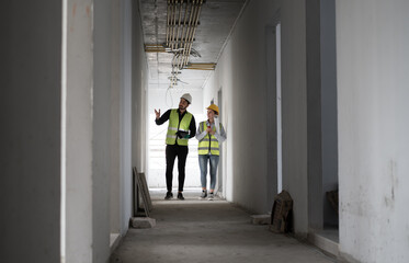 Caucasian engineer man and woman working with tablet computer and paper work in building at construction site	