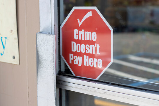 "Crime Doesn't Pay Here" warning signage at the entrance to a retail store. Organized retail crime (ORC) concept.