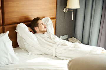 Young man resting on a large bed