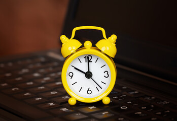 Alarm clock on a laptop keyboard, time management or save time background