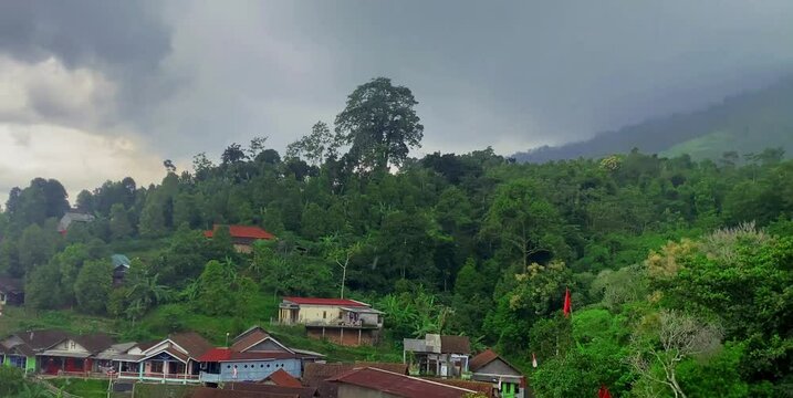 view of people's houses interspersed with trees on the slopes of the mountains when it rains