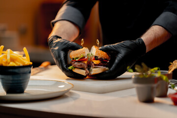 Professional kitchen in hotel restaurant chef shows cut delicious juicy burger close up
