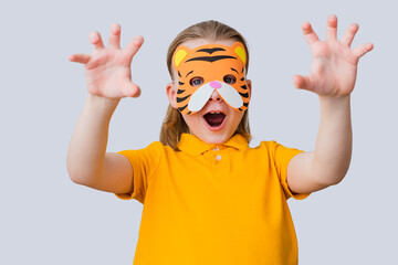 The roar of a tiger, isolated on gray background. A child in a handmade carnival mask. Play...