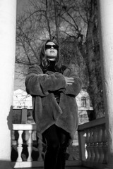 Attractive woman in park, posing dressed in a orange gloves and blue fur coat, with long red curly hair, sunset background.