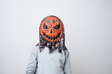Child wearing pumpkin vinyl mask on a gray background. Halloween holiday or a birthday party. Early...