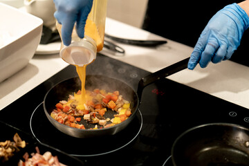 close-up of a chef in an open kitchen in a hotel preparing an omelette with vegetables during...