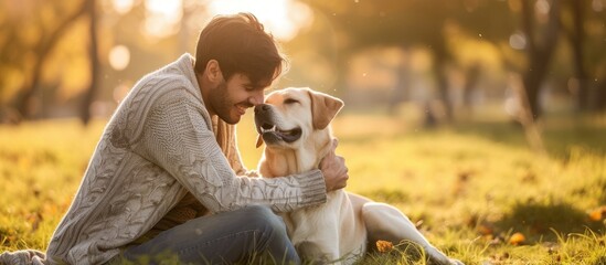 Attractive man with Labrador retriever outside on green grass.