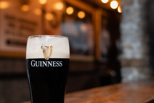 Pint of dark beer Guinness in glass on blurred background of Irish pub. Ireland, Dublin, January 20, 2024
