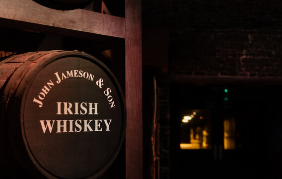 Vintage Irish whiskey barrel John Jameson and Son in basement on blurred dark background. Ireland, Midleton, 22 January 2024