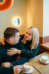 Love romantic couple lovestory. Man hugging woman, kissing blonde girl in cozy coffee shop cafe. Romantic family date. Sitting at window table in restaurant. Intimate romance atmosphere