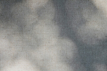 Beige fabric texture background with shadows of natural sunlight.