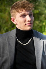 jeune homme en costume gris avec un collier de perles de culture