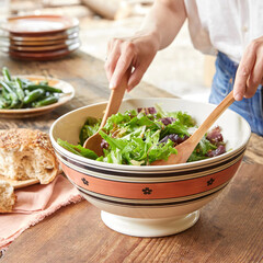 close up of woman hands mix salad with wooden spoons