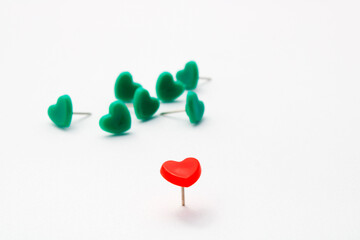 Red heart shaped thumbtack leading a green group