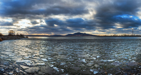 The lake landscape of Musov Czech Republic. View of Lake Musovske and Palava in the Czech Republic. Ice floes in the foreground. In the background, a TV transmitter and the ruins of Devicky Castle.