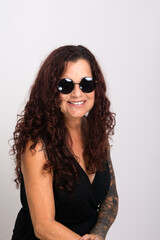 Beautiful curly-haired woman wearing sunglasses and black clothing smiling.