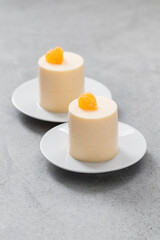 Tangerine Cream Panna Cotta of cylindrical shape.On a plate. Light grey background. 