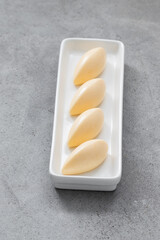 Vegan Tangerine cream dessert quenelle, on a serving plate. Light gray background. Close up