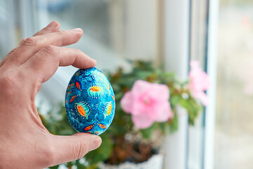 Ukrainian Easter egg with Petrykivka painting in the palm. Hand painted wooden decor.