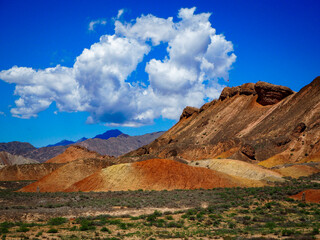 Colourful rocks and peak with cloud hanging over the mountains