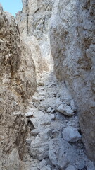 Steiler schmaler Wanderweg Klettersteig zwischen den Felsen führt hoch hinaus. Im Hintergrund blauer Himmel.  Weg in den Alpen Dolomiten. Schroffe karge Felswand im Gebirge. im Gebirge..