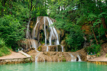 Lucansky waterfall in the village of Lucky - water flows down a travertine rock from a small height among greenery. The waterfall never freezes, because water from hot springs flows through it.
