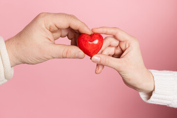 closeup hands holding heart on pink background, valentine's day concept