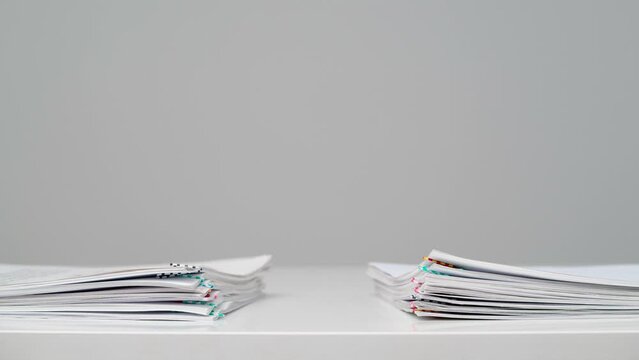 Time lapse studio shot of paper sheets. Stop motion animation of two stacks business or educational paper documents with paper clips.