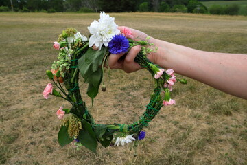 Midsummer wreath made of wild flowers. Held by female hand. Swedish tradition.