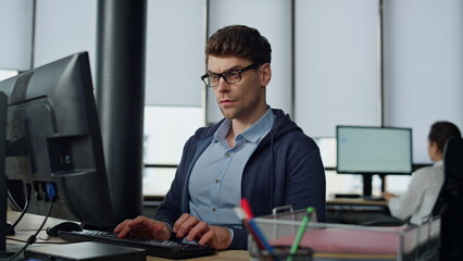 Serious it guy typing computer in office. Professional programmer code using two
