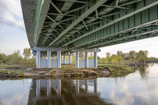 Bottom view of the metal structure of a road bridge, construction of a road across the river.