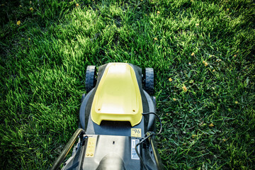 top view of yellow lawn mower in green grass