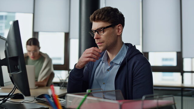 Thoughtful programmer looking computer at desk. Focused it man analysing code