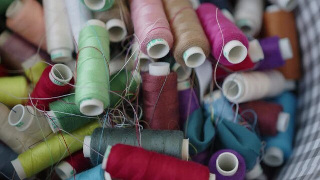Multi colored sewing threads on spools in a basket. Extreme close-up view, background video