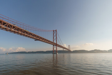 Red bridge 25 de Abril Bridge and statue of Cristo Rei during a slightly misty day, Lisbon, Portugal