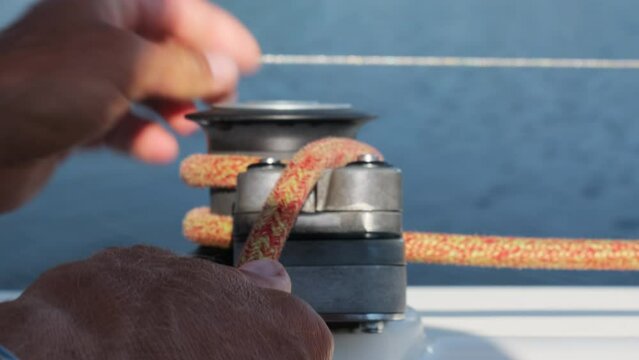 Skillful sailor fixes sails by wrapping rope around halyard. Captain of sailboat exactly knows how to guide vessel in right place