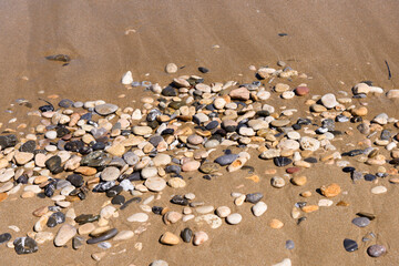 Smooth colorful wet pebble stones background on the beach.