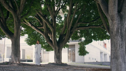 Chic lady standing square calling in elegant white suit. Woman talking on phone 