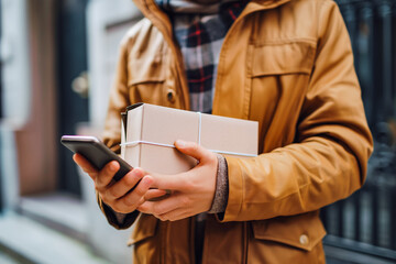 Close up courier holding package and smart phone requesting signature for delivery.