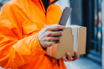 Close up courier holding package and smart phone requesting signature for delivery.