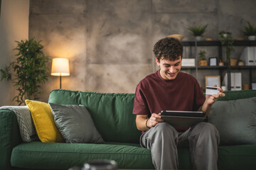 teenager young man sit at home use credit card shopping online